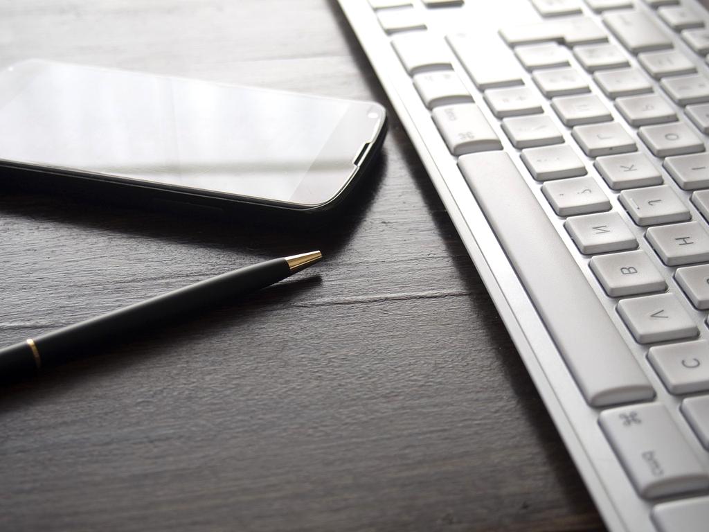 Hands organizing office desk with accessories and stationery